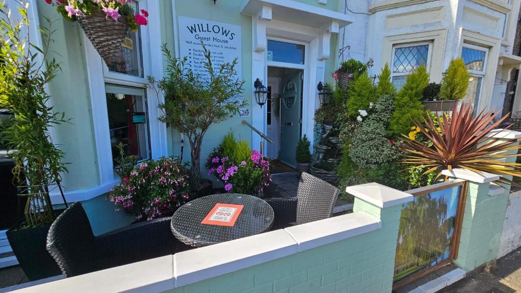 a table in front of a building with flowers at Willows Guest House in Great Yarmouth