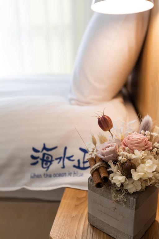 a vase with flowers on a table next to a bed at Blue Lagoon in Huxi