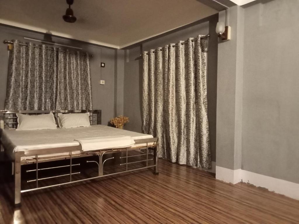 een slaapkamer met een bed en een raam met gordijnen bij Ellys home stay in Guwahati