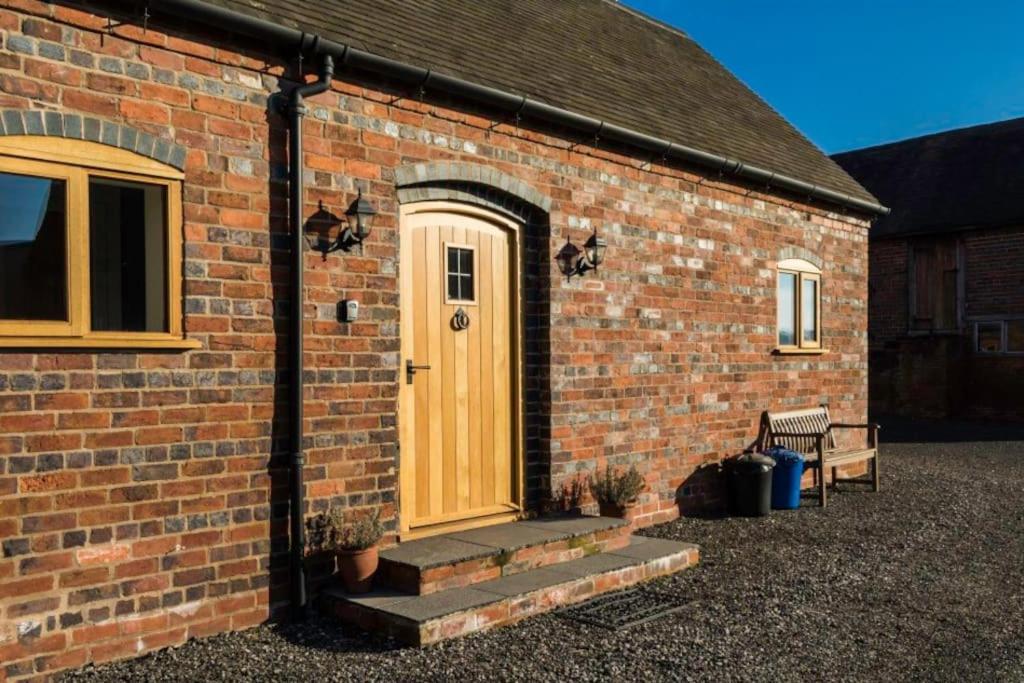 uma casa de tijolos com uma porta de madeira e escadas em The Little Dairy em Stourbridge