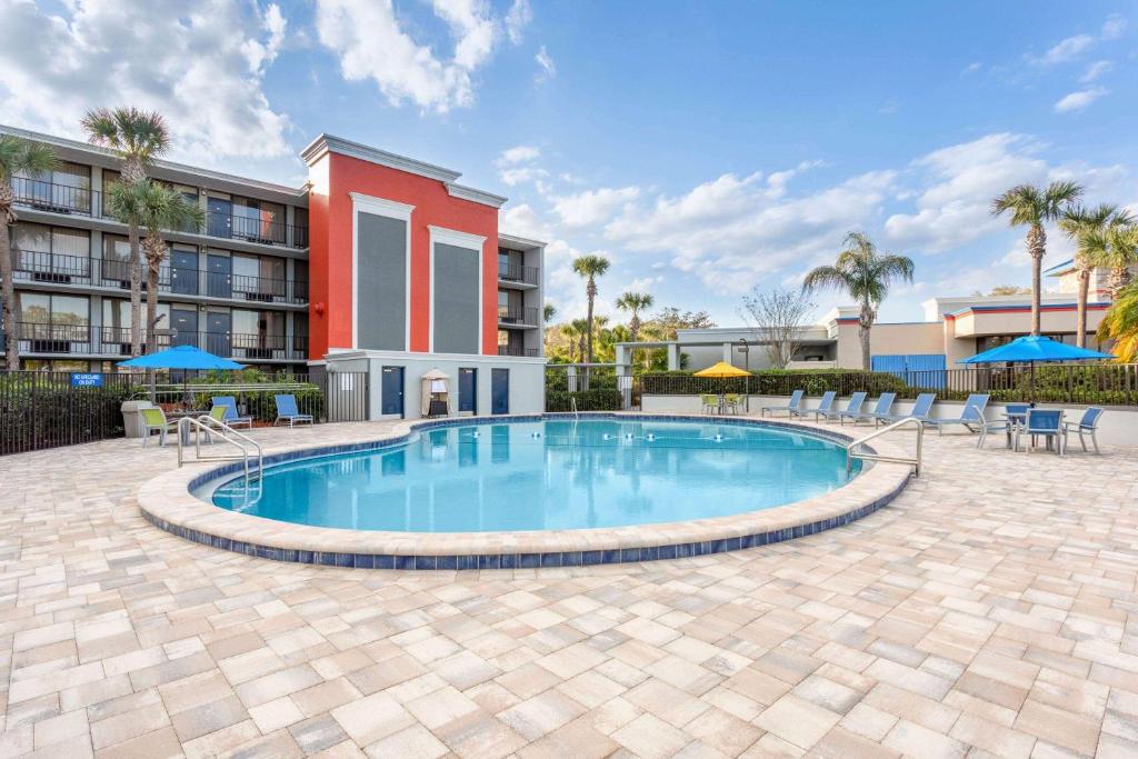 una piscina con mesas y sillas y un edificio en Days Inn by Wyndham Orlando Conv. Center/International Dr en Orlando