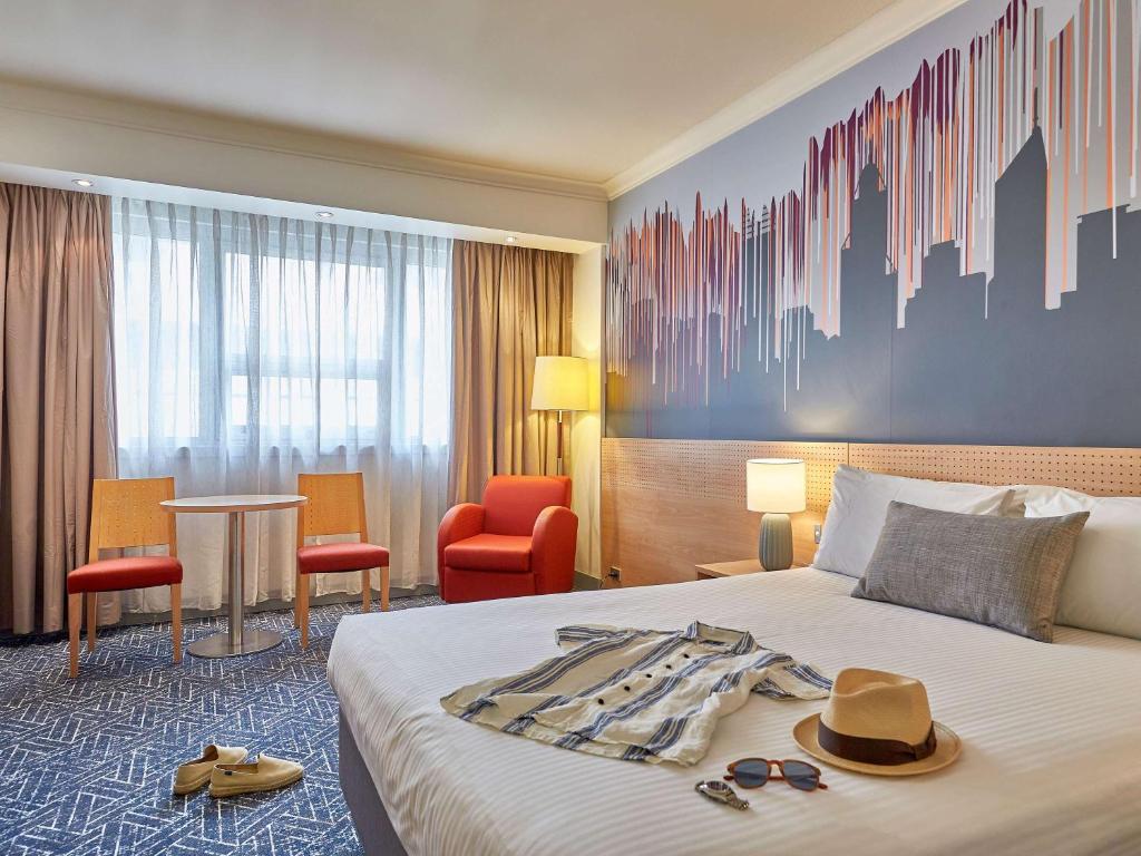 une chambre d'hôtel avec un lit doté de chapeaux et de lunettes de soleil dans l'établissement Mercure Perth, à Perth