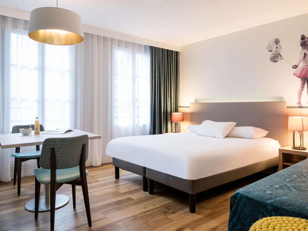 a hotel room with a bed and a desk and a table at Aparthotel Adagio Paris Montmartre in Paris