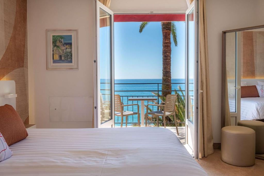 a bedroom with a bed and a view of the ocean at Best Western Premier Hotel Prince de Galles in Menton
