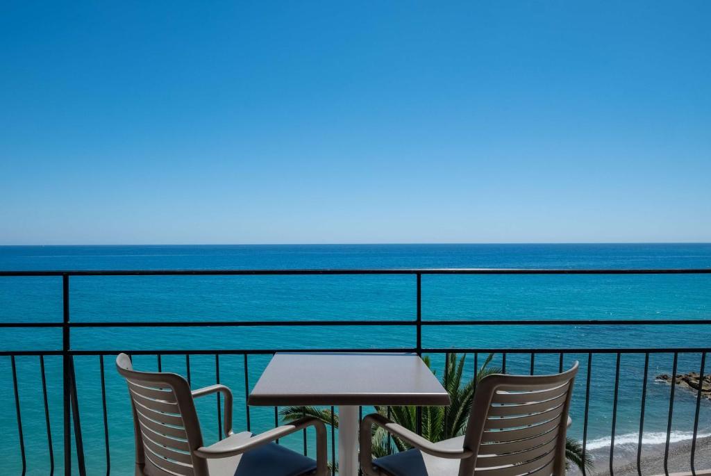 d'une table et de chaises sur un balcon donnant sur l'océan. dans l'établissement Best Western Premier Hotel Prince de Galles, à Menton