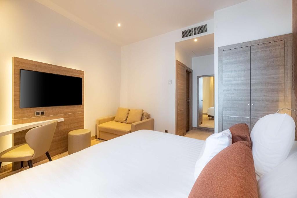 a bedroom with a bed and a desk and a television at Best Western Premier Hotel Prince de Galles in Menton