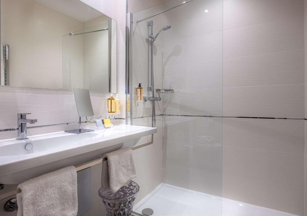 a bathroom with a sink and a glass shower at Best Western Premier Hotel Prince de Galles in Menton