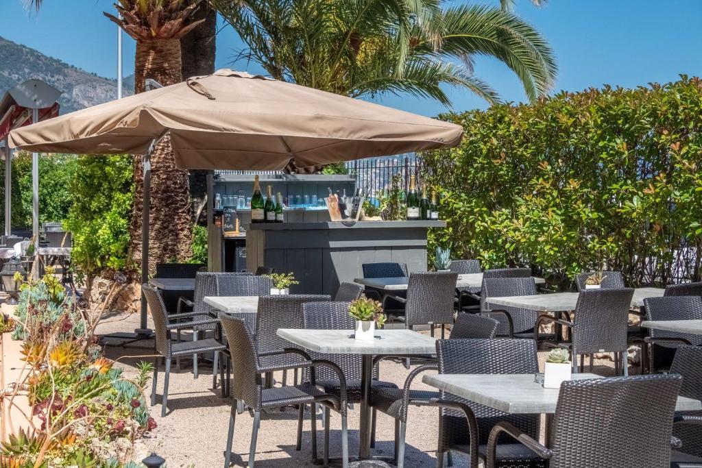 a patio with tables and chairs and an umbrella at Best Western Premier Hotel Prince de Galles in Menton