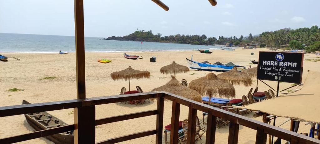 a beach with some straw umbrellas and the ocean at On the beach in Palolem