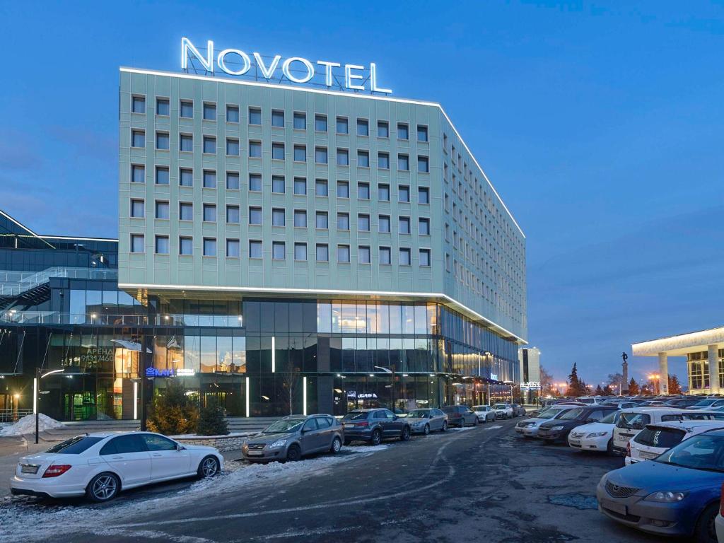 a hotel with cars parked in a parking lot at Novotel Krasnoyarsk Center in Krasnoyarsk