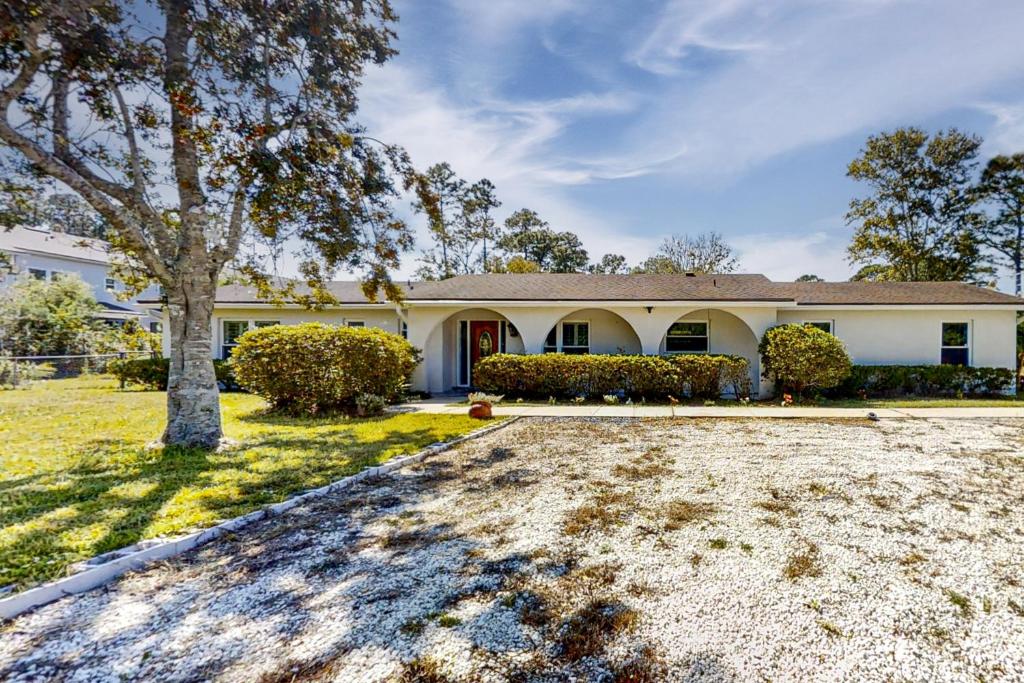 a large white house with a tree in the yard at By the Beach - Full Property in Jacksonville