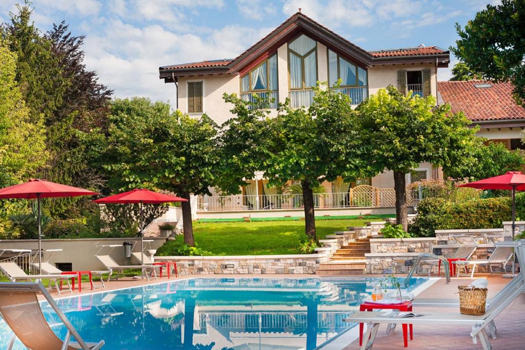 a pool with chairs and umbrellas in front of a house at Olea Dei Holiday Apartments in San Felice del Benaco