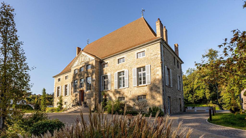 ein altes Steingebäude mit braunem Dach in der Unterkunft Domaine de Dolomieu Hotel & Spa - BW Premier Collection in Dolomieux