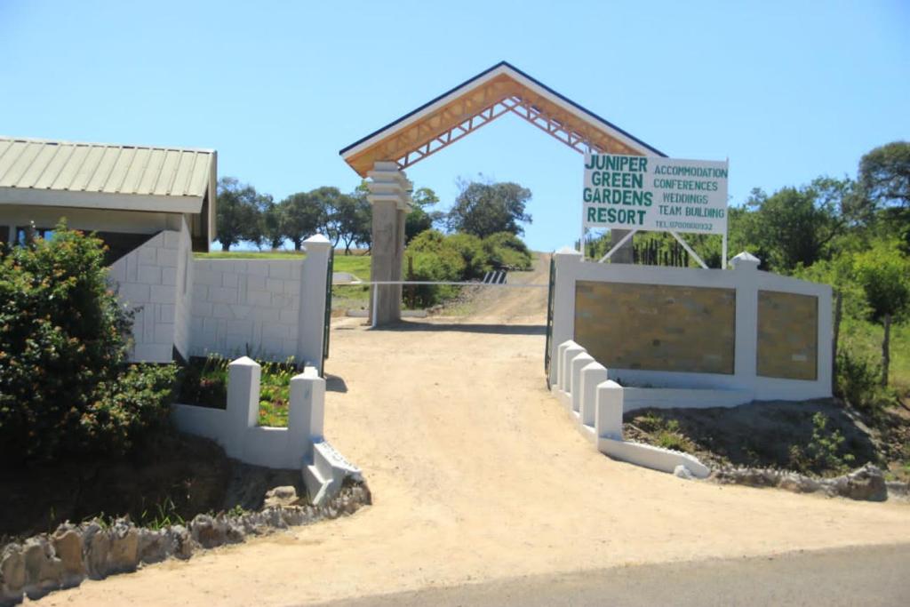 un cancello con un cartello di fronte a un edificio di Juniper Green Gardens Resort. a Mweiga