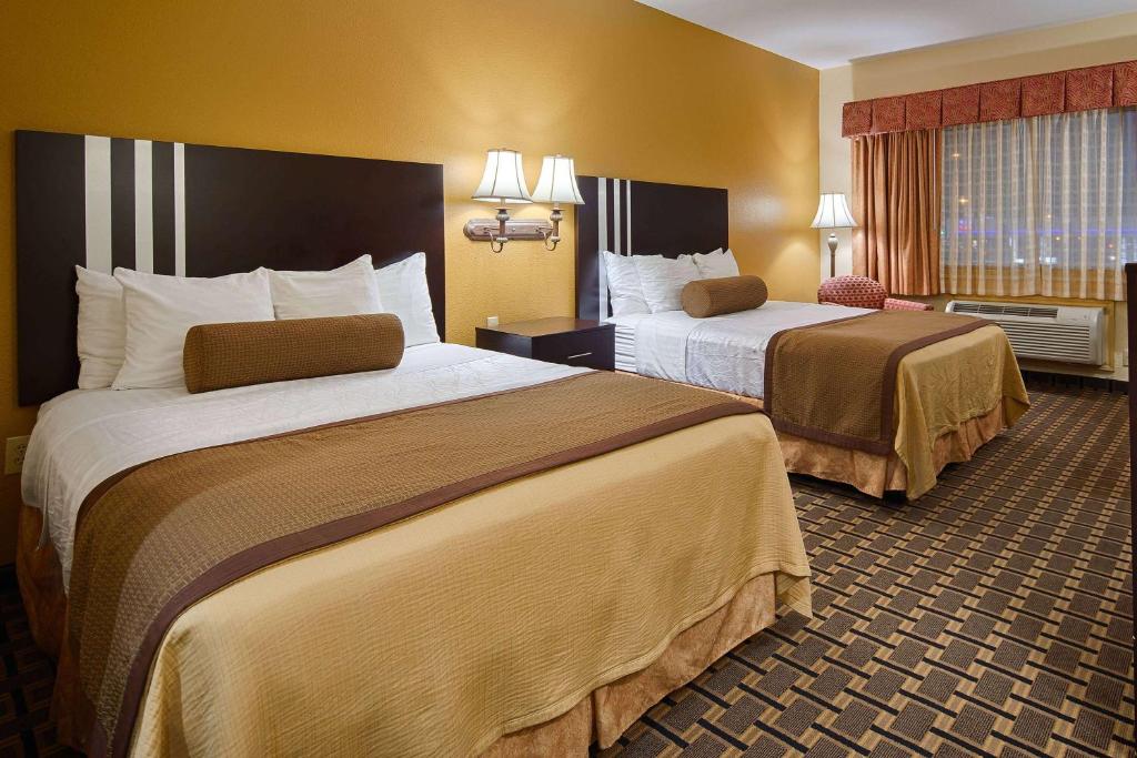 a hotel room with two beds in a room at Days Inn & Suites by Wyndham Sam Houston Tollway in Houston