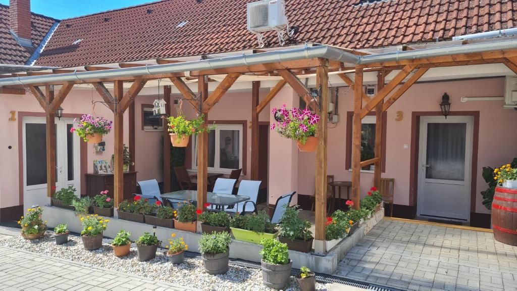 a house with a patio with a table and flowers at Pikoló Vendéglő és Vendégház in Bakonybél