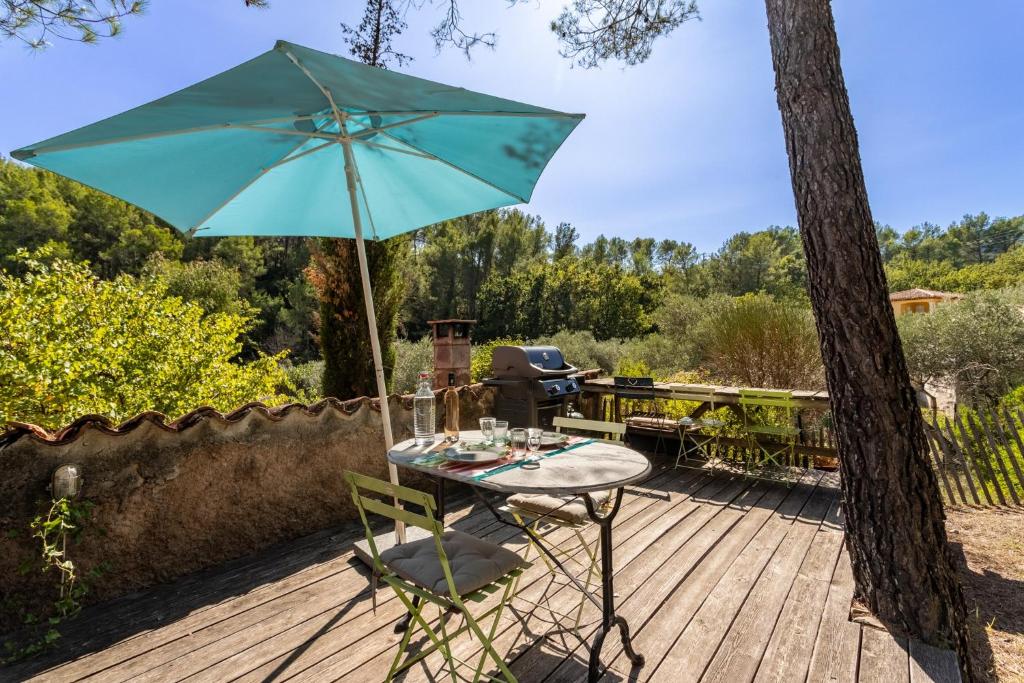 uma mesa e cadeira com um guarda-chuva num deque em Gite l'Instant - Au cœur d'une oliveraie em Belgentier
