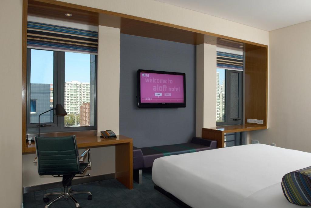 um quarto de hotel com uma cama, uma secretária e uma televisão em Aloft Beijing, Haidian em Pequim