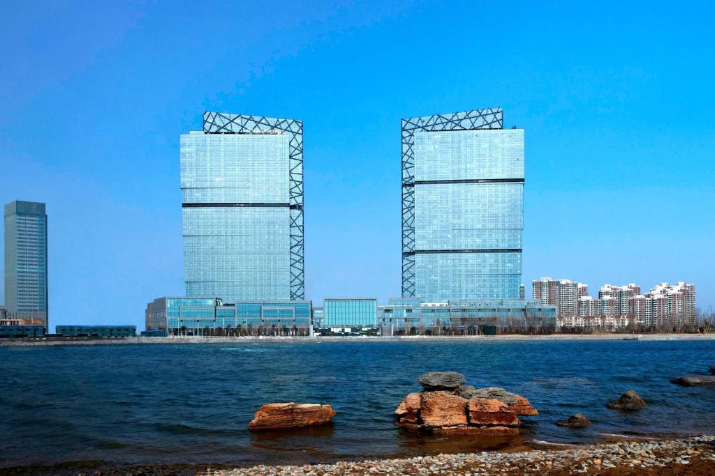 dois edifícios altos em frente a um corpo de água em Four Points by Sheraton Qingdao, West Coast em Huangdao