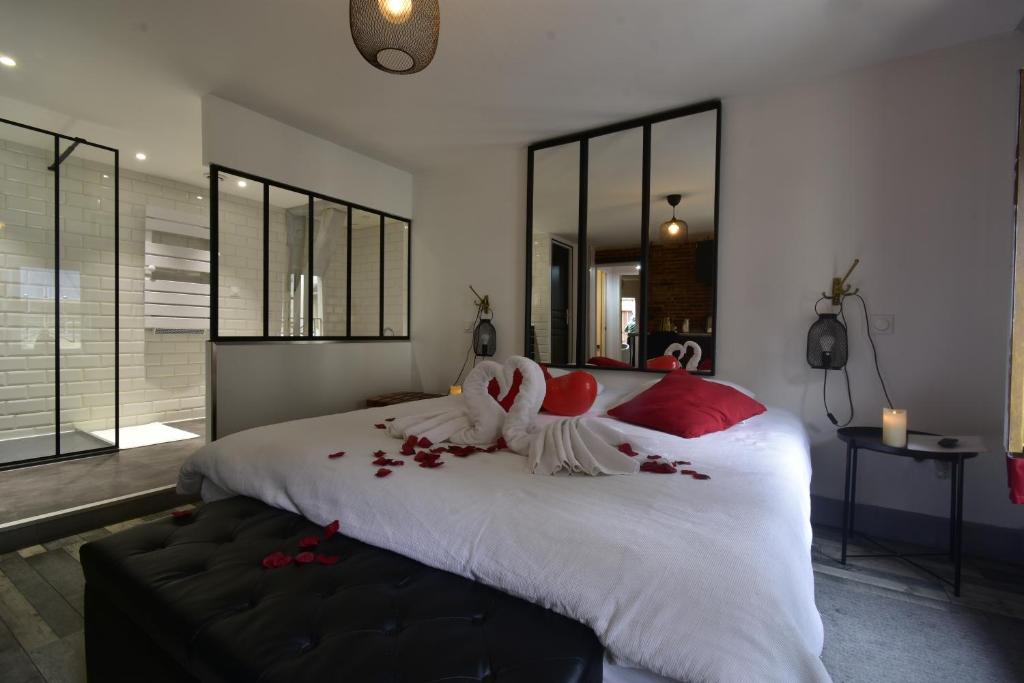 una camera da letto con un grande letto bianco con cuscini rossi di Appartement jacuzzi privatif : Urban Love a Verneuil d'Avre et d'Iton