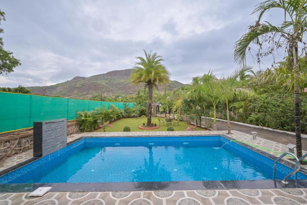 a swimming pool in a resort with a mountain in the background at Lifeline Villas - The Secret Place Lonavala With Huge Pool And Lawn Area in Lonavala