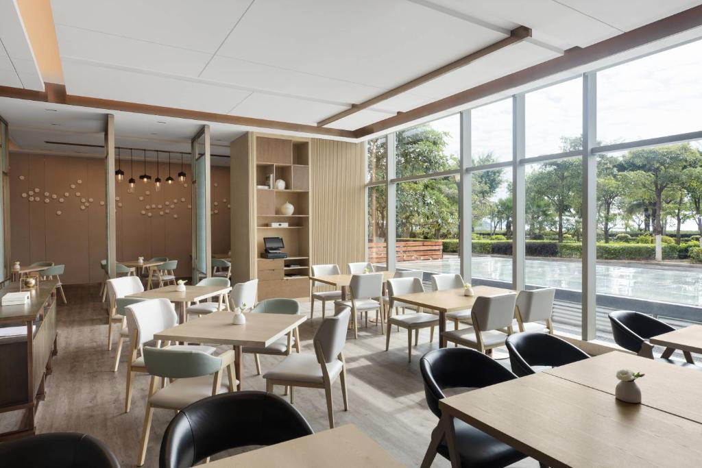 a restaurant with tables and chairs and large windows at Courtyard by Marriott Xiamen Haicang in Xiamen