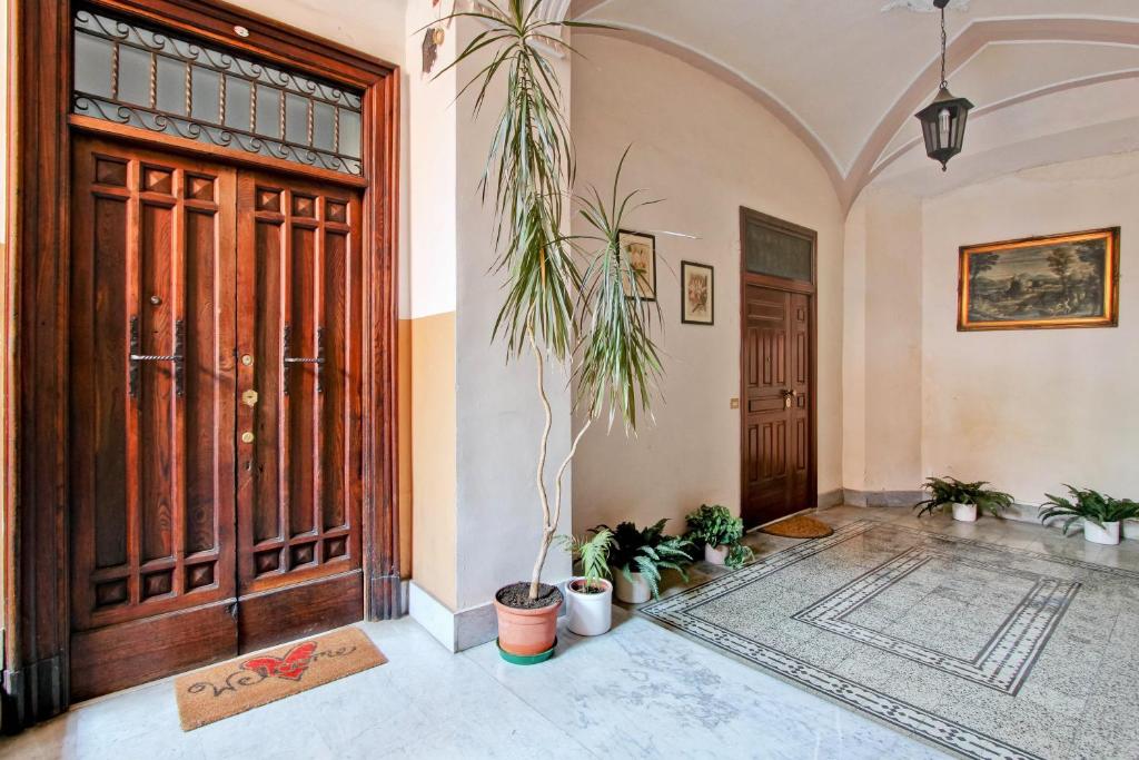 un couloir avec une porte et des plantes devant lui dans l'établissement Domvs Romae Apartment, à Rome