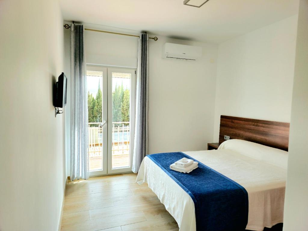 a bedroom with a bed and a sliding glass door at Hostal Restaurante el cruce in Padul