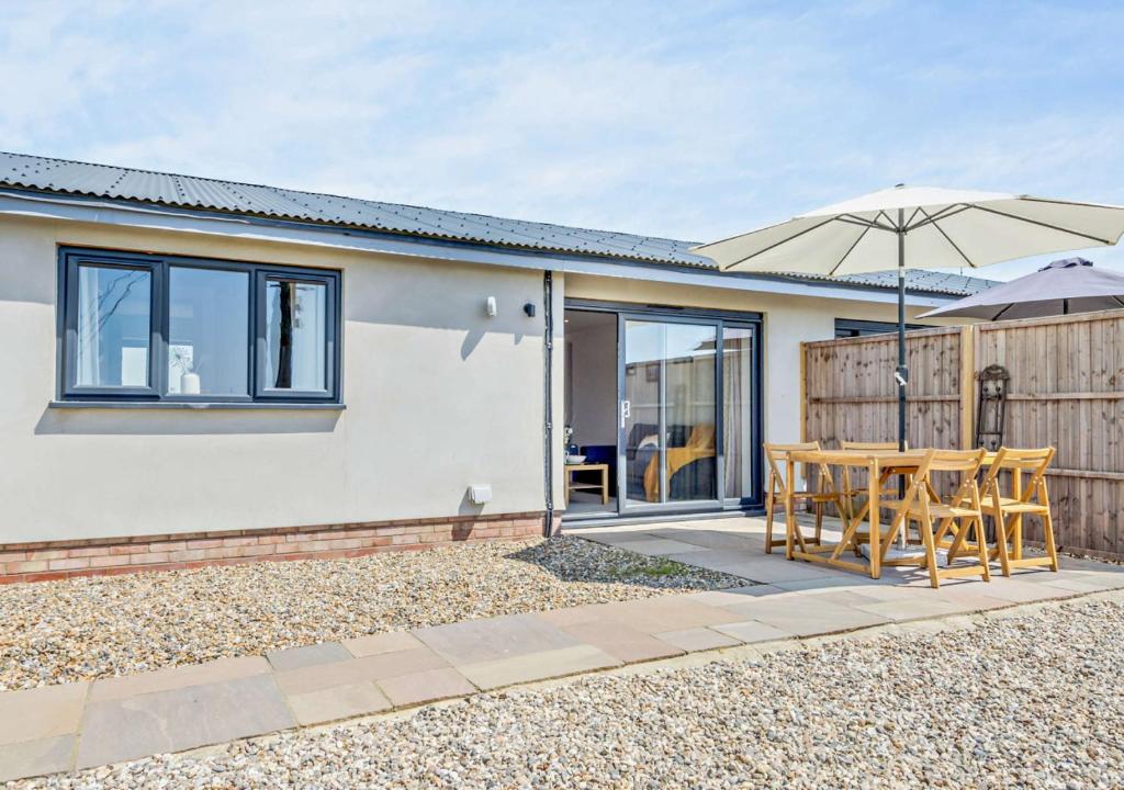 Cette maison dispose d'une terrasse avec une table et un parasol. dans l'établissement Grove Farm Cottage, à Worlingworth