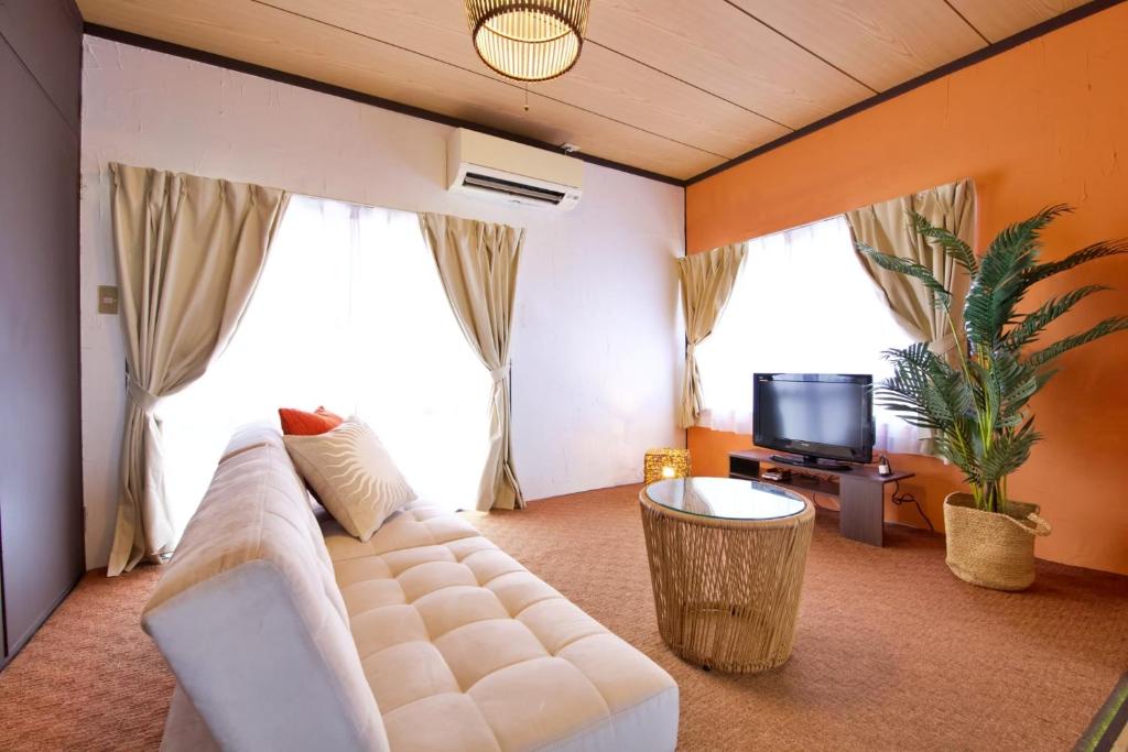 Una sala de estar con un sofá blanco y un televisor. en パイナガマビーチハウス 301, en Isla Miyako