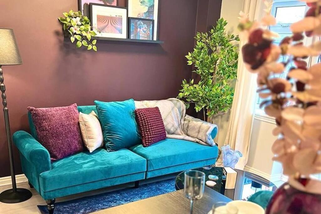 a living room with a green couch with colorful pillows at Damson Drive- Boutique Home in Oldbury