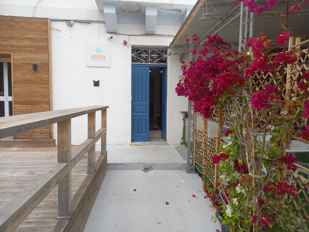 a blue door on the side of a building with flowers at Cresta Beach Studios in St. Julianʼs