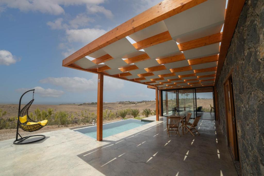 um pátio exterior com uma piscina e uma pérgola de madeira em Casa Julie em Chilegua