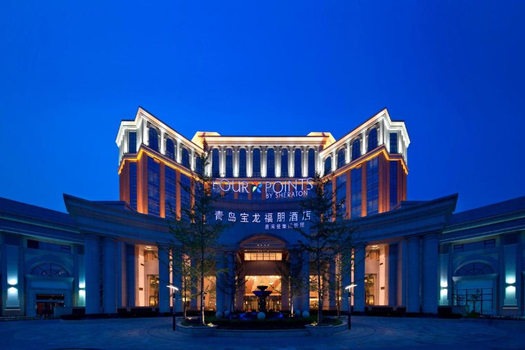 un grand bâtiment avec un panneau la nuit dans l'établissement Four Points by Sheraton Qingdao, Chengyang, à Qingdao