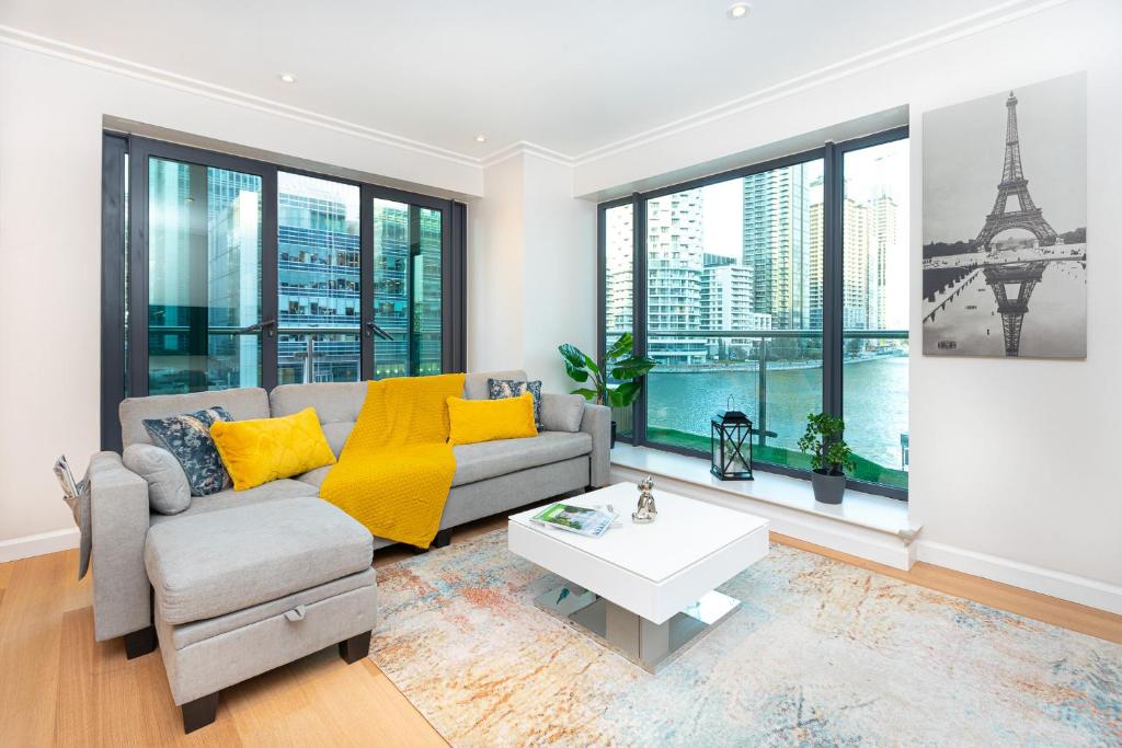 Luxurious Modern 3BR Flat in Prime Canary Wharf في لندن: غرفة معيشة مع أريكة وطاولة