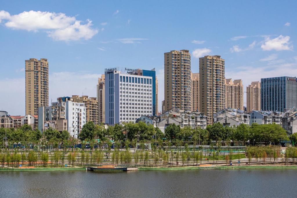 Fairfield by Marriott Jingzhou في Jingzhou: أفق المدينة مع مباني طويلة وجسم من المياه
