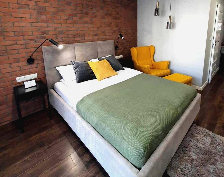 グダニスクにあるHello Apartments Modern Industrial Browar Gdańskiのベッドルーム(大型ベッド1台、黄色い椅子付)