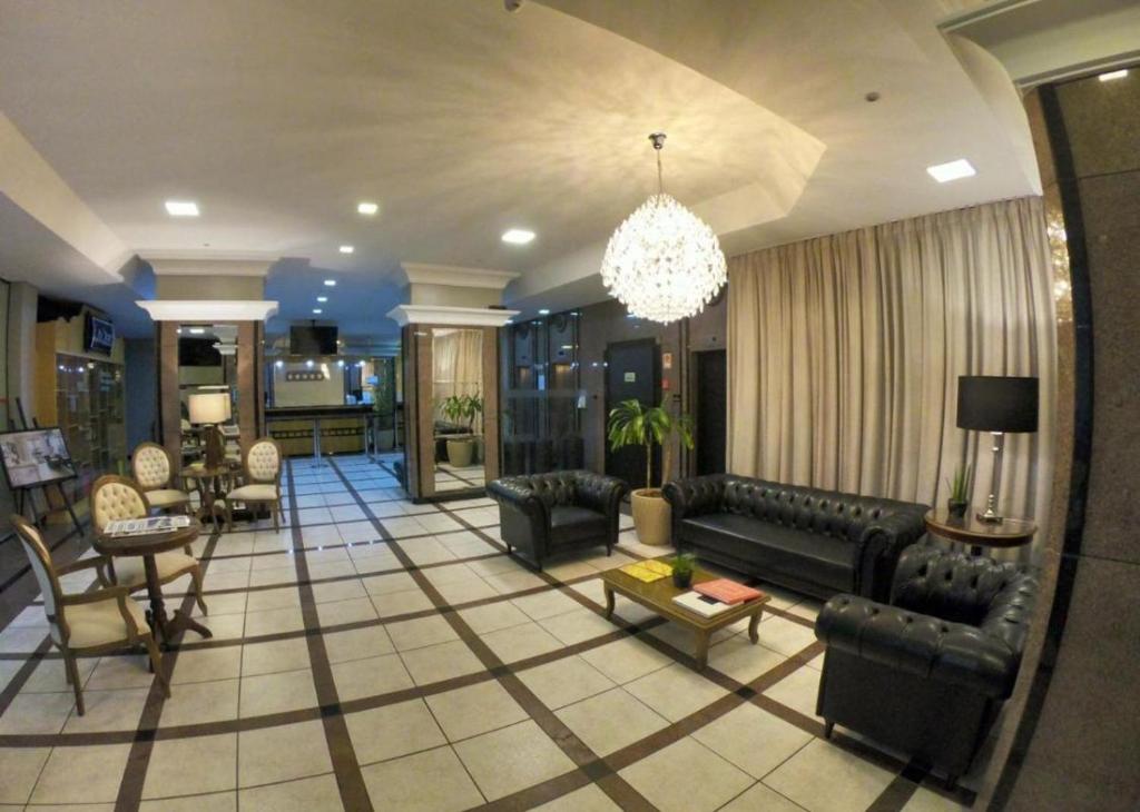 una gran sala de estar con sofás y una lámpara de araña. en Aquarius Flat Studio 601, en Santa Cruz do Sul