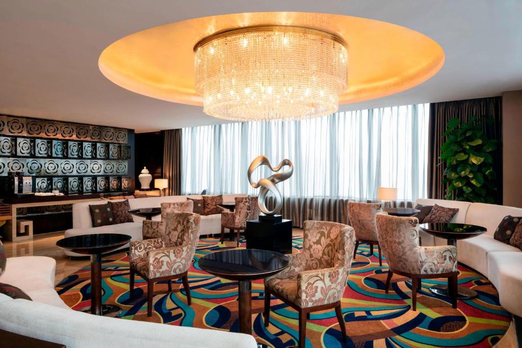 un vestíbulo con una lámpara de araña, mesas y sillas en Sheraton Wuxi Binhu Hotel en Wuxi