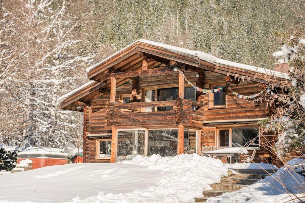 una cabaña de madera en la nieve con nieve en el suelo en Spectacular Chalet with 5 ensuite bedrooms and sauna, en Chamonix-Mont-Blanc