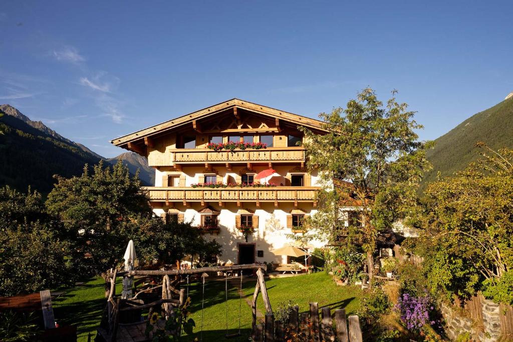 um grande edifício com uma varanda numa colina em Fleckhof em Neustift im Stubaital