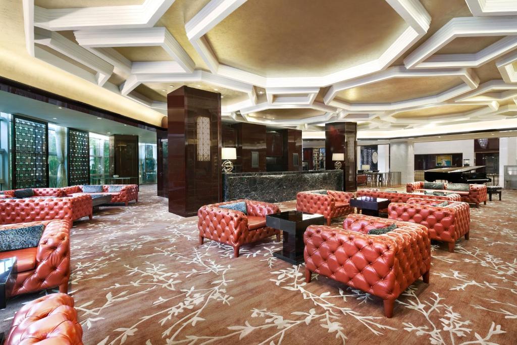 a hotel lobby with red chairs and a piano at Sheraton Shanghai Waigaoqiao Hotel in Shanghai