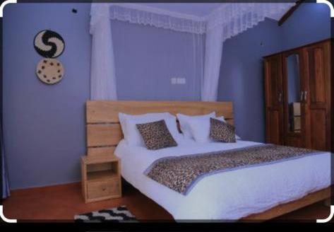 a bedroom with a large bed with white sheets and pillows at KIZUNGU FOREST COTTAGES & SPA in Kampala