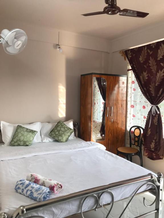 - une chambre avec un lit doté de draps blancs et une fenêtre dans l'établissement Living Roots Lodge, à Cherrapunji