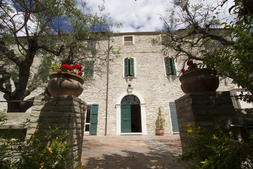 ein Steinhaus mit zwei großen Vasen mit Blumen darauf in der Unterkunft Villa le Colline - Homelike Villas in Cingoli
