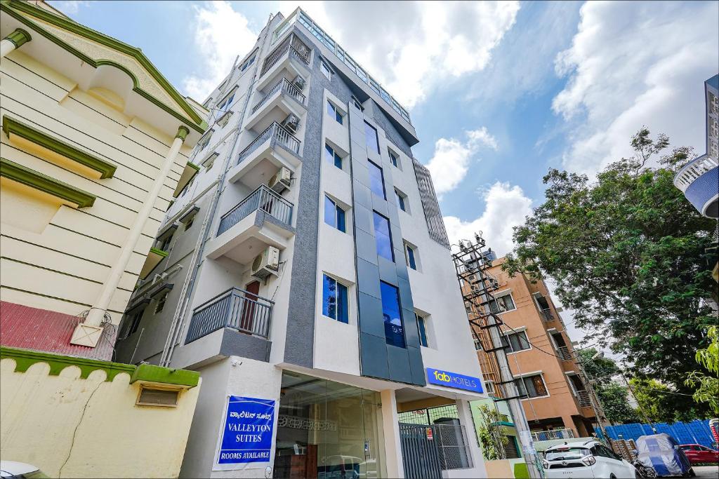 a tall white building with blue windows on a street at FabHotel Crystal Suites - Near Marathahalli Junction in Bengaluru