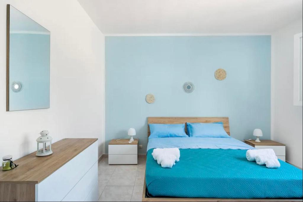 una camera da letto con un letto blu e uno specchio di Villa Le Conche - Sunset a Marina di Lizzano