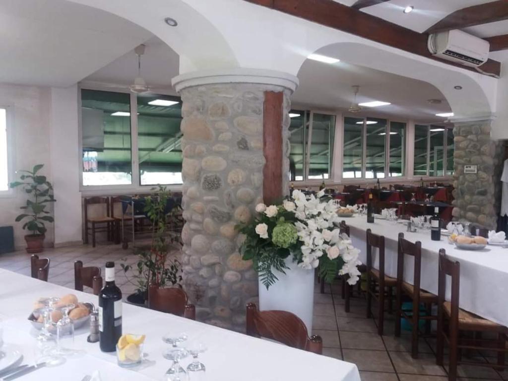 un restaurante con mesas y sillas blancas y un pilar de piedra en Mambly b&b ristorante pizzeria, en Galliate