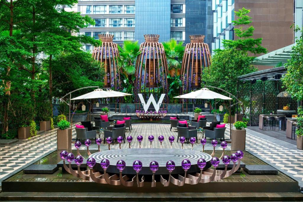 a courtyard with a fountain with purple flowers and umbrellas at W Guangzhou in Guangzhou