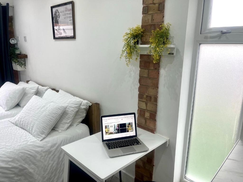 a laptop computer sitting on a table next to a bed at Nice and Cosy Large Studio near Luton Airport in Luton
